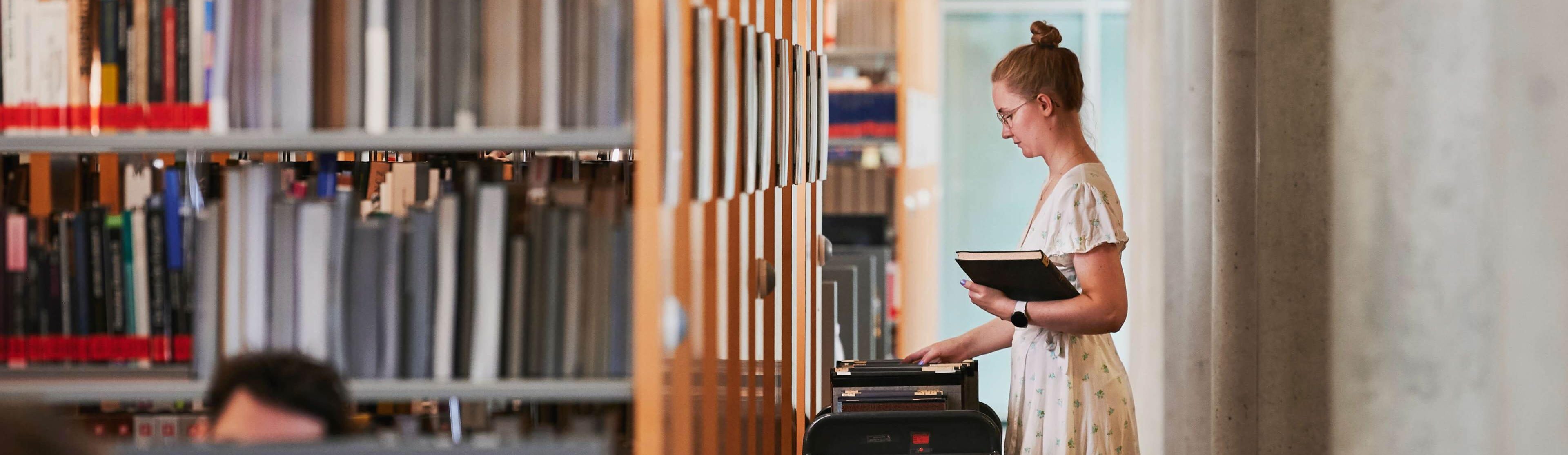 Bibliothek im Karlsruher Institut für Technologie (KIT) Eine Frau steht vor einem Regal in einer Bibliothek